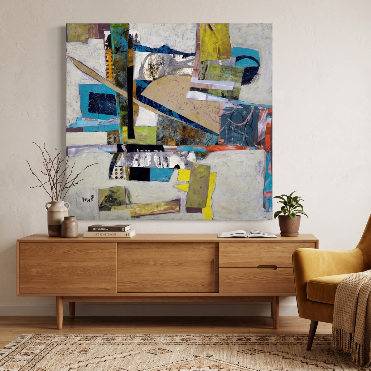 A large abstract canvas art print with a patchwork collage design in blue, yellow, beige, and gray, displayed on a beige wall above a mid-century modern wooden credenza in a styled living room.