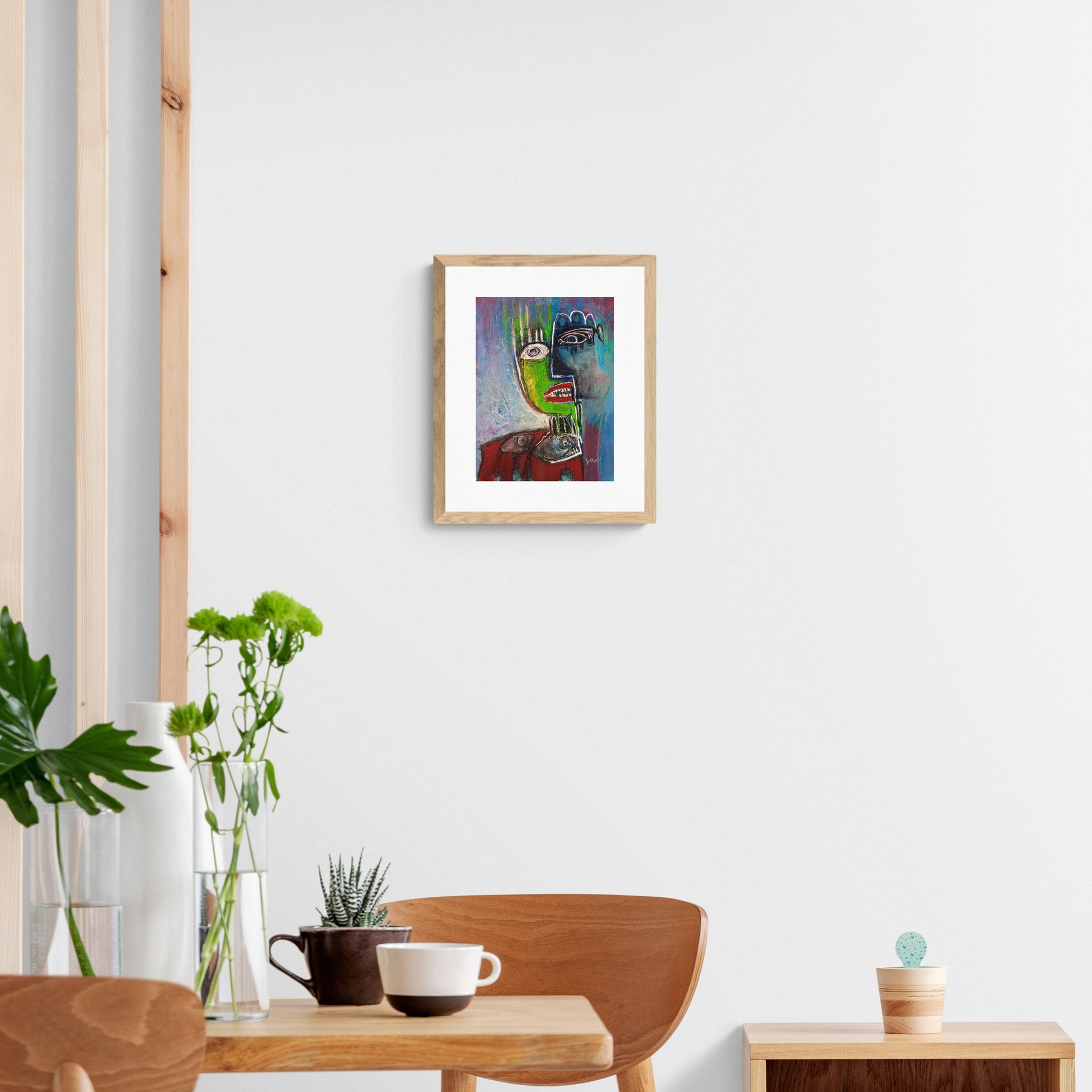 Modern interior with a framed picture on the wall, table with plants, and cup.
