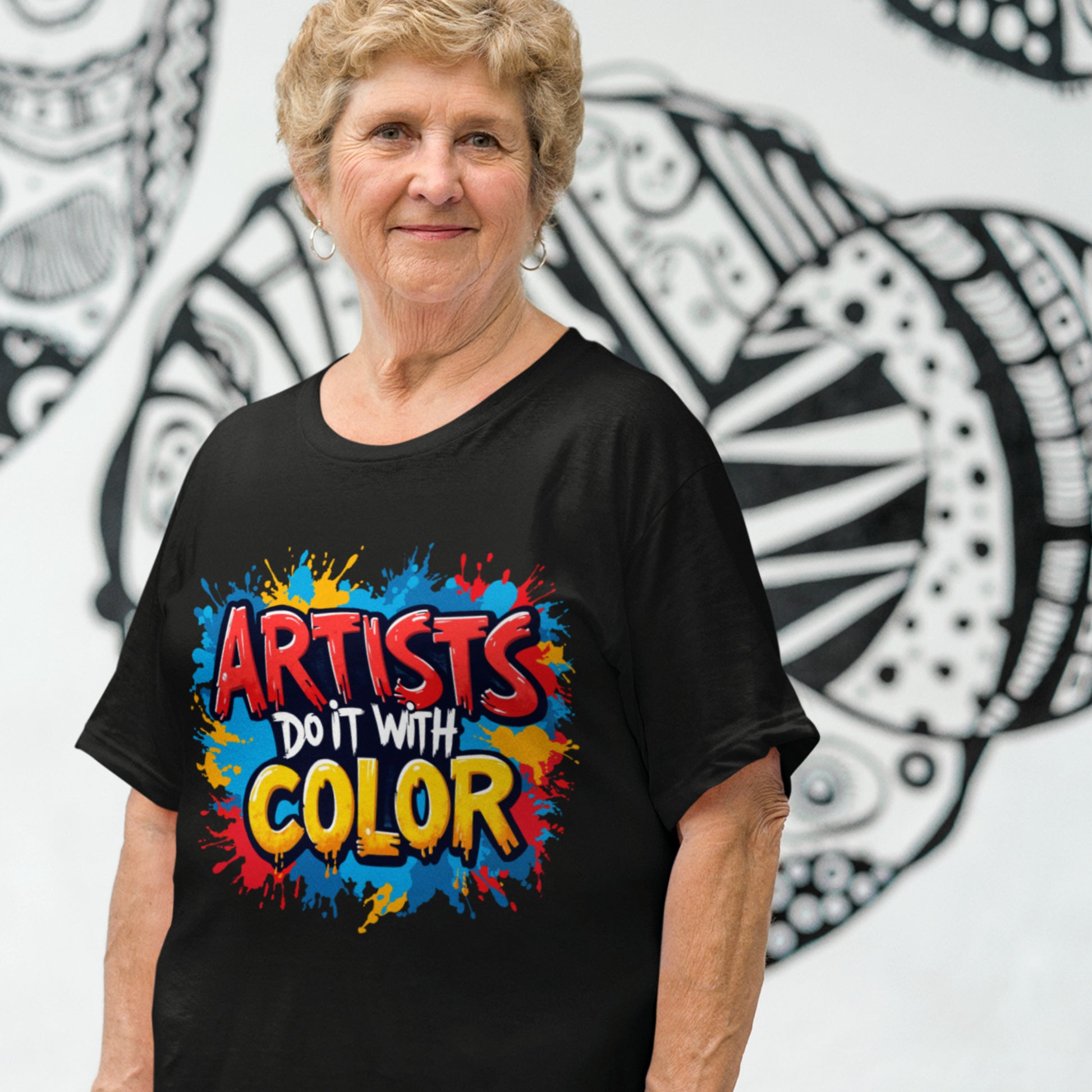 Woman wearing a black t-shirt with colorful text in front of a wall with abstract designs.