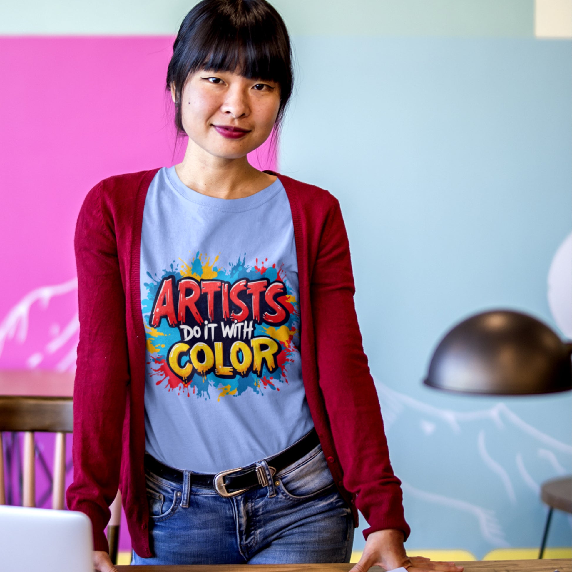 Person wearing a t-shirt with 'Artists Do It With Color' design in a casual setting.