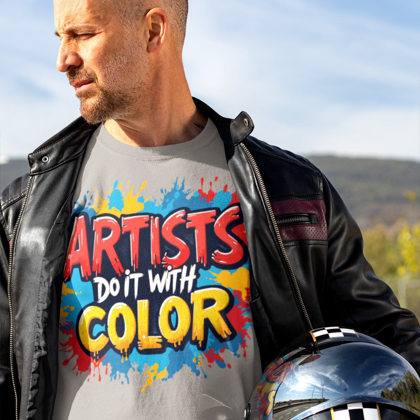 Man wearing a t-shirt with 'Artists Do It With Color' design outdoors.