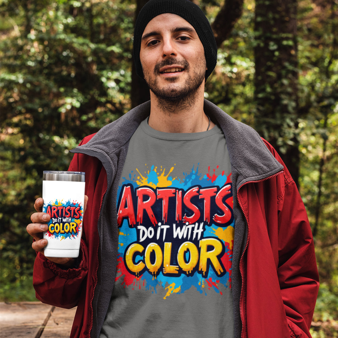 Man wearing a 'Artists Do It With Color' shirt holding a tumbler in a forest setting