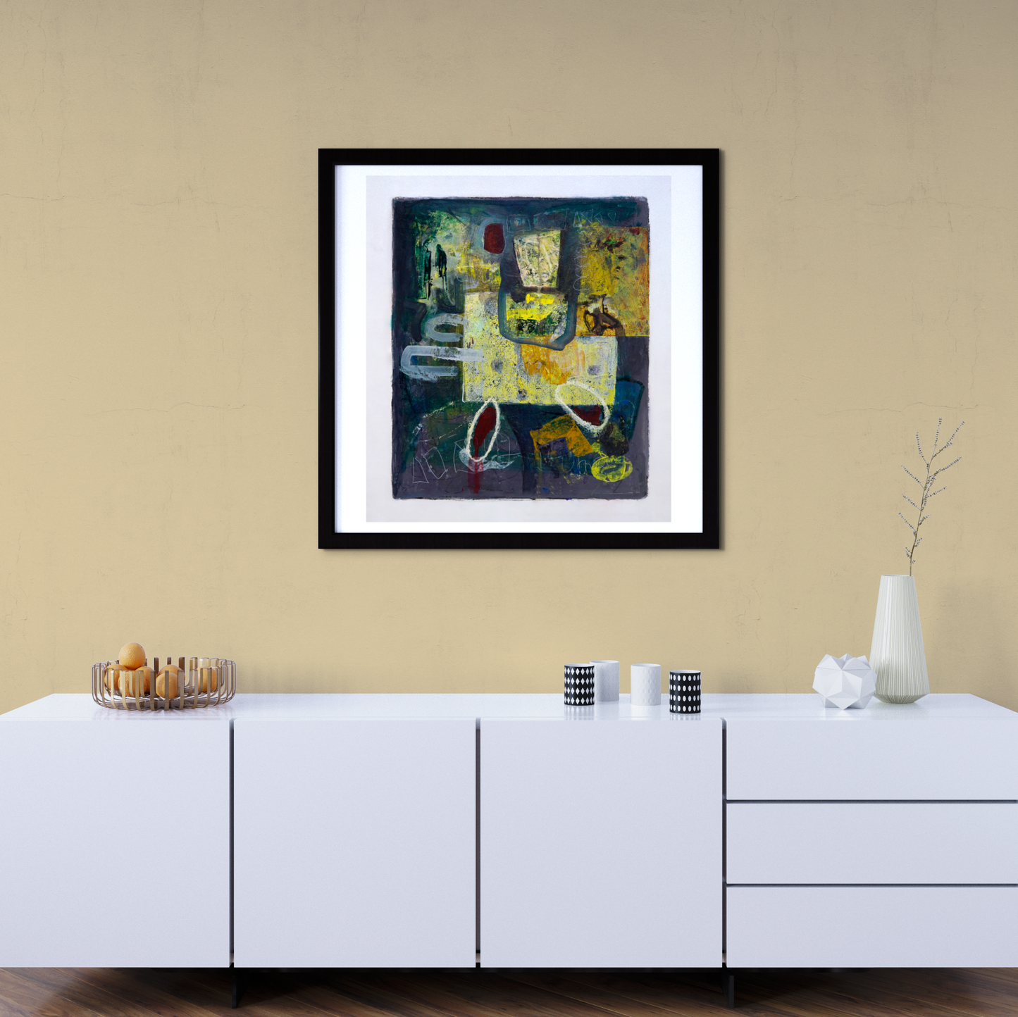 Framed abstract painting on a beige wall above a white cabinet.