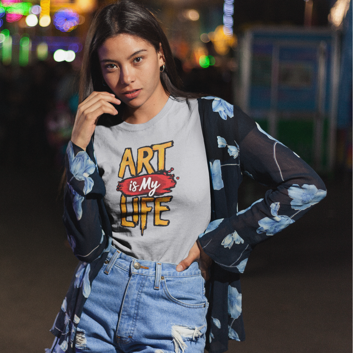Woman wearing a 'Art is My Life' t-shirt at a nighttime fair.