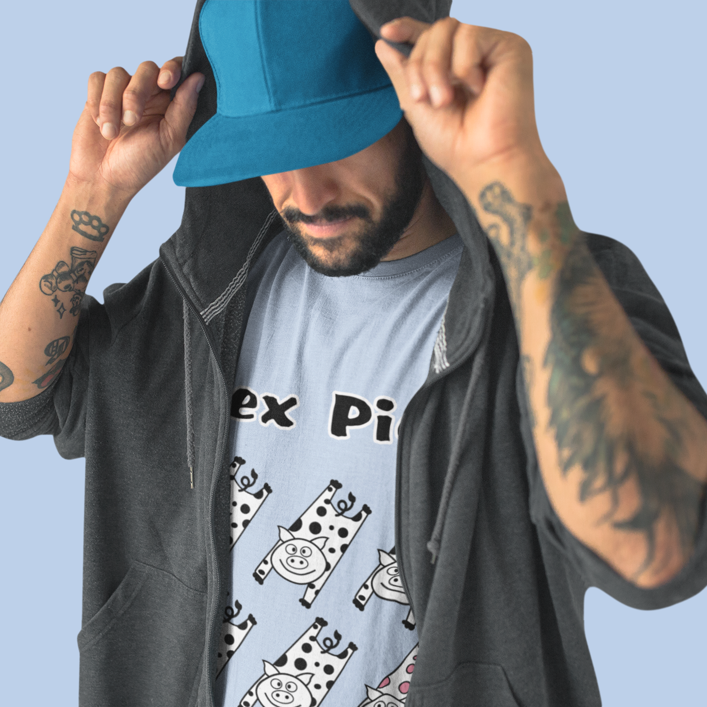 Person wearing a blue cap and gray jacket with a graphic t-shirt on a light blue background