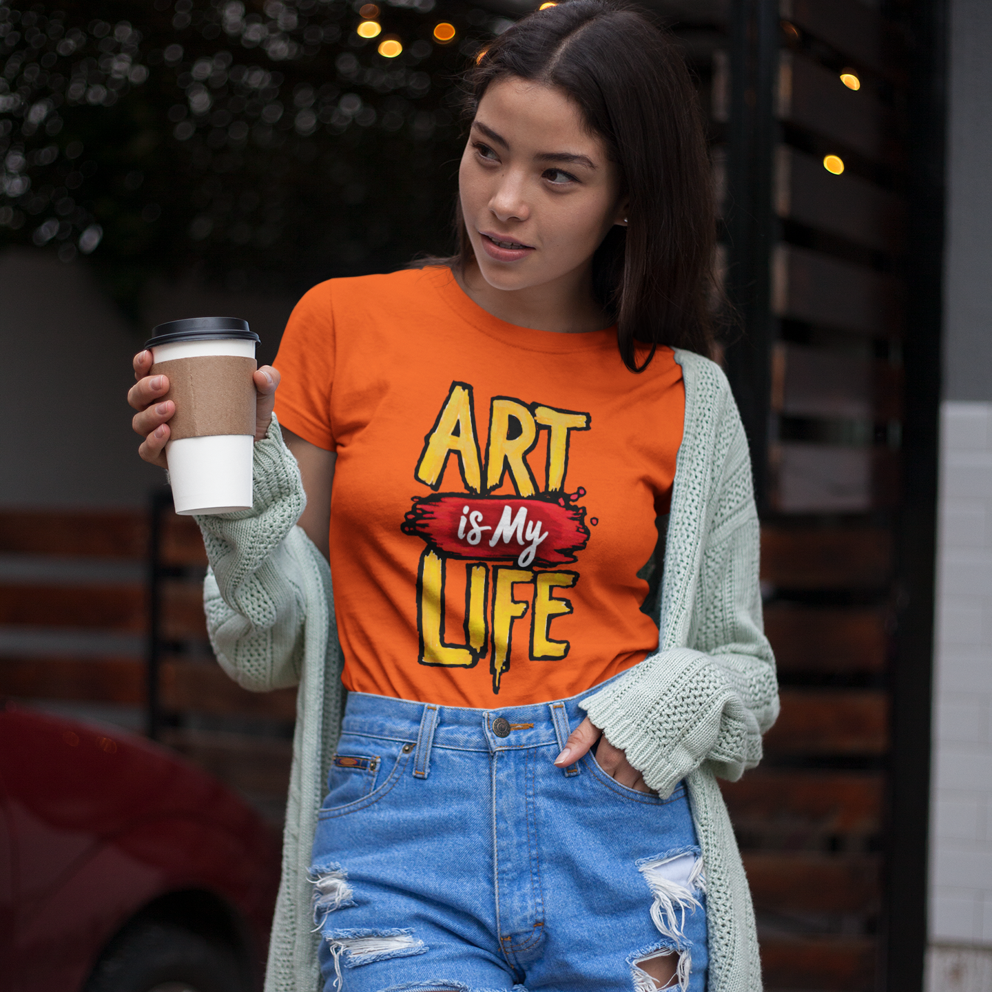 Woman wearing an 'Art is My Life' t-shirt holding a coffee cup outdoors.
