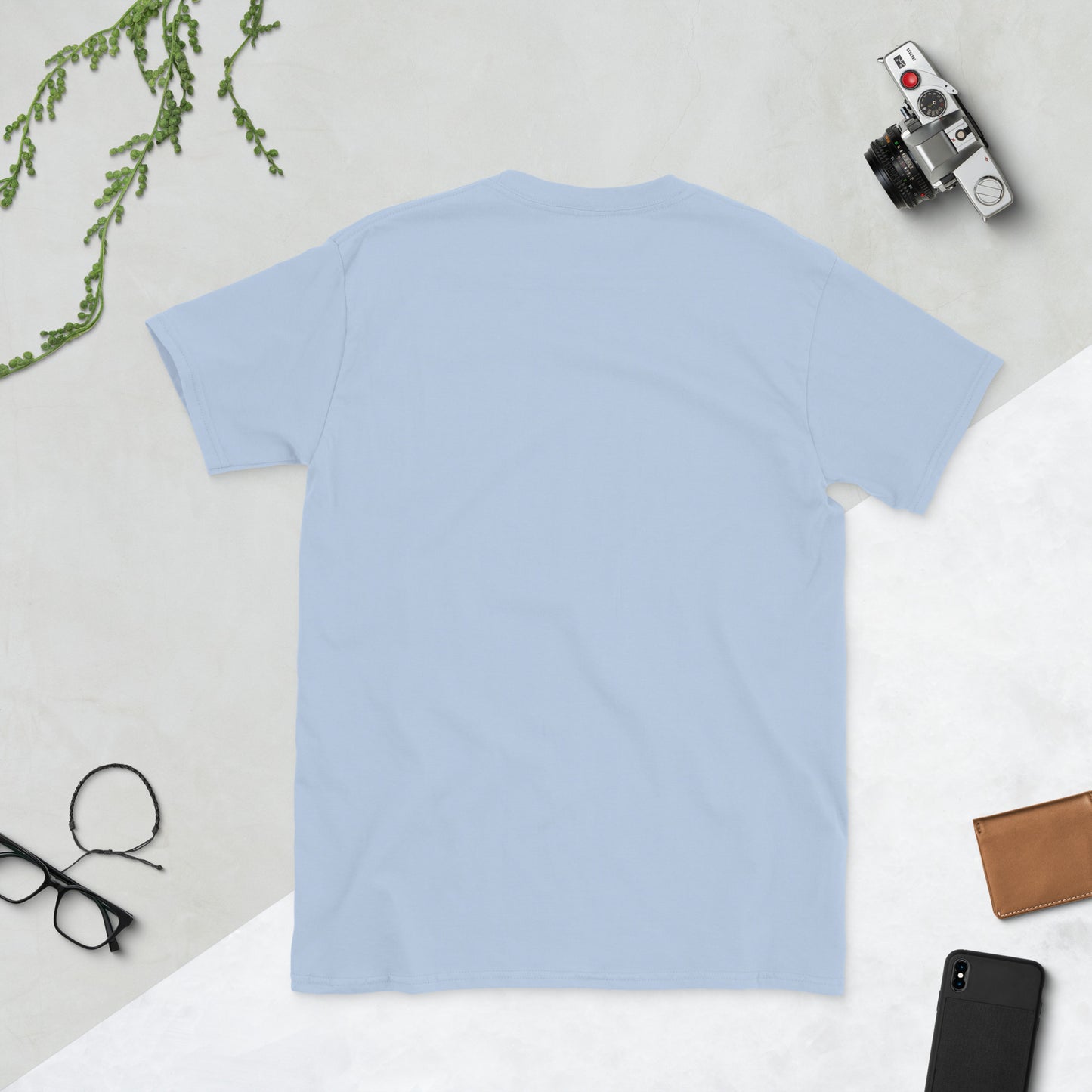 Plain light blue t-shirt on a white surface with accessories around