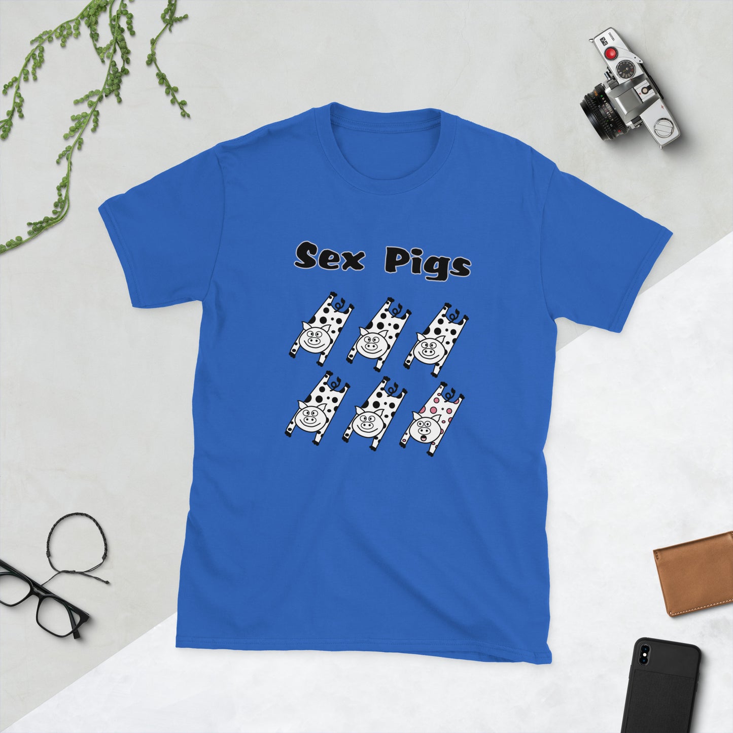 Blue t-shirt with 'Sex Pigs' graphic on a light gray surface with accessories.