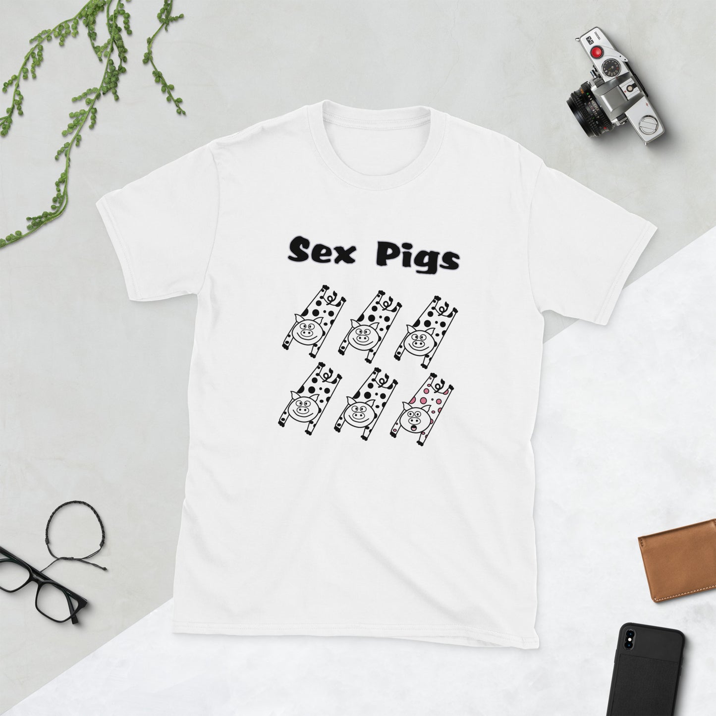 White t-shirt with 'Sex Pigs' graphic design on a light gray surface with accessories.