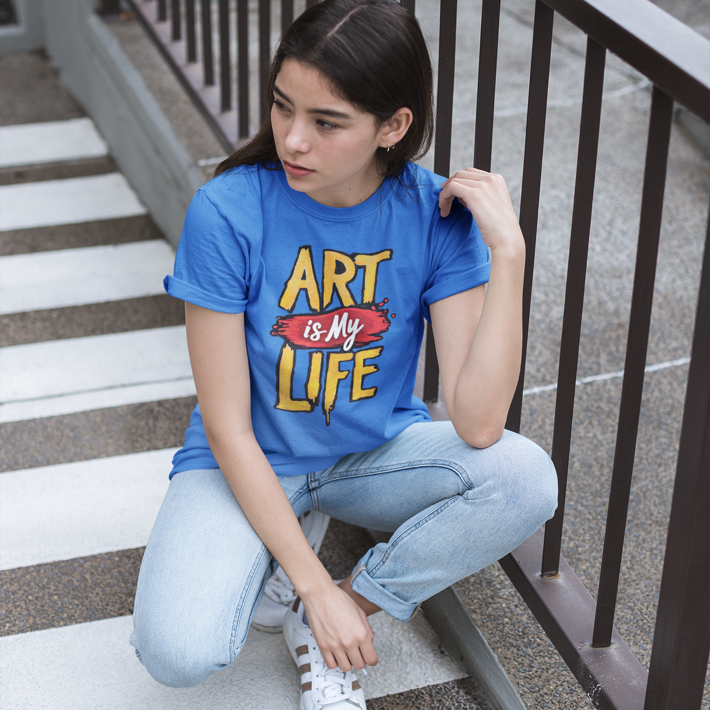 Person wearing a blue t-shirt with 'Art is My Life' text sitting on steps.